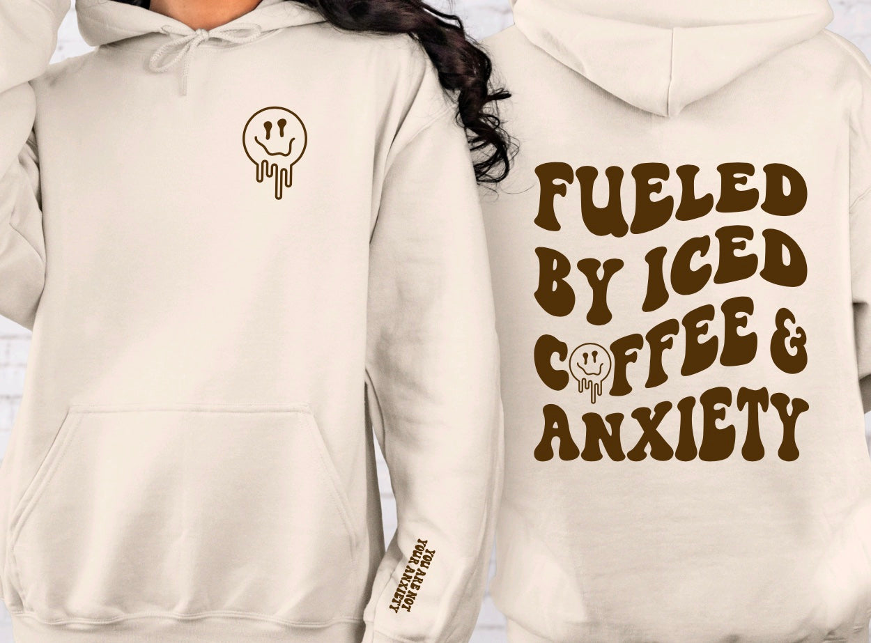 Fueled by iced coffee and anxiety unisex hoodie with front and back graphic in sand with brown graphic and daily reminder on sleeve
